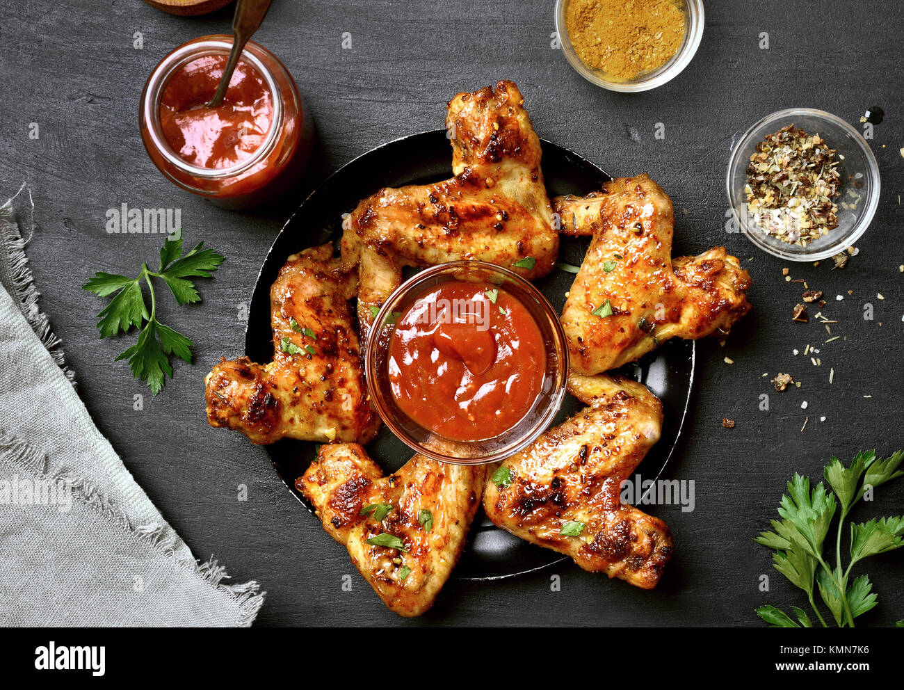 Alette di pollo fritte con salsa su sfondo scuro. Vista superiore, laici piatta Foto Stock