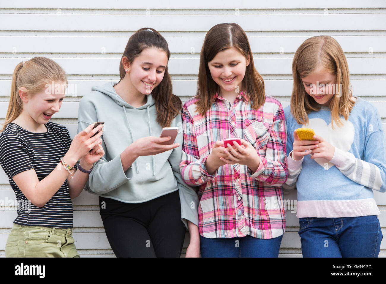 Un gruppo di giovani ragazze all'esterno guardando i messaggi su telefoni cellulari Foto Stock