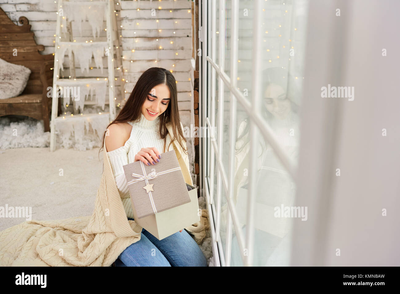 La ragazza alla finestra con doni per l'inverno. Foto Stock