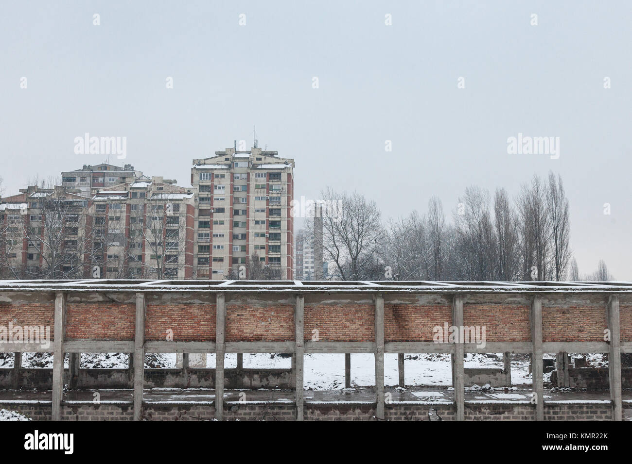 Alloggiamento comunista edifici nella parte anteriore di un magazzino abbandonato in Pancevo, Serbia, durante un pomeriggio freddo sotto la neve. Questo tipo di torri sono un s Foto Stock