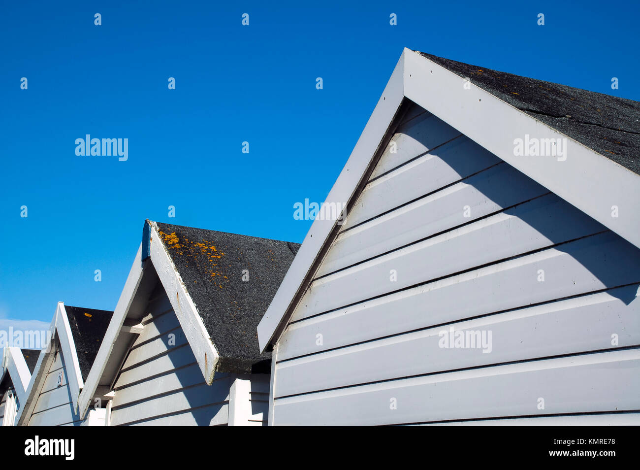Una linea di cabine sulla spiaggia, contro un luminoso cielo blu. Foto Stock