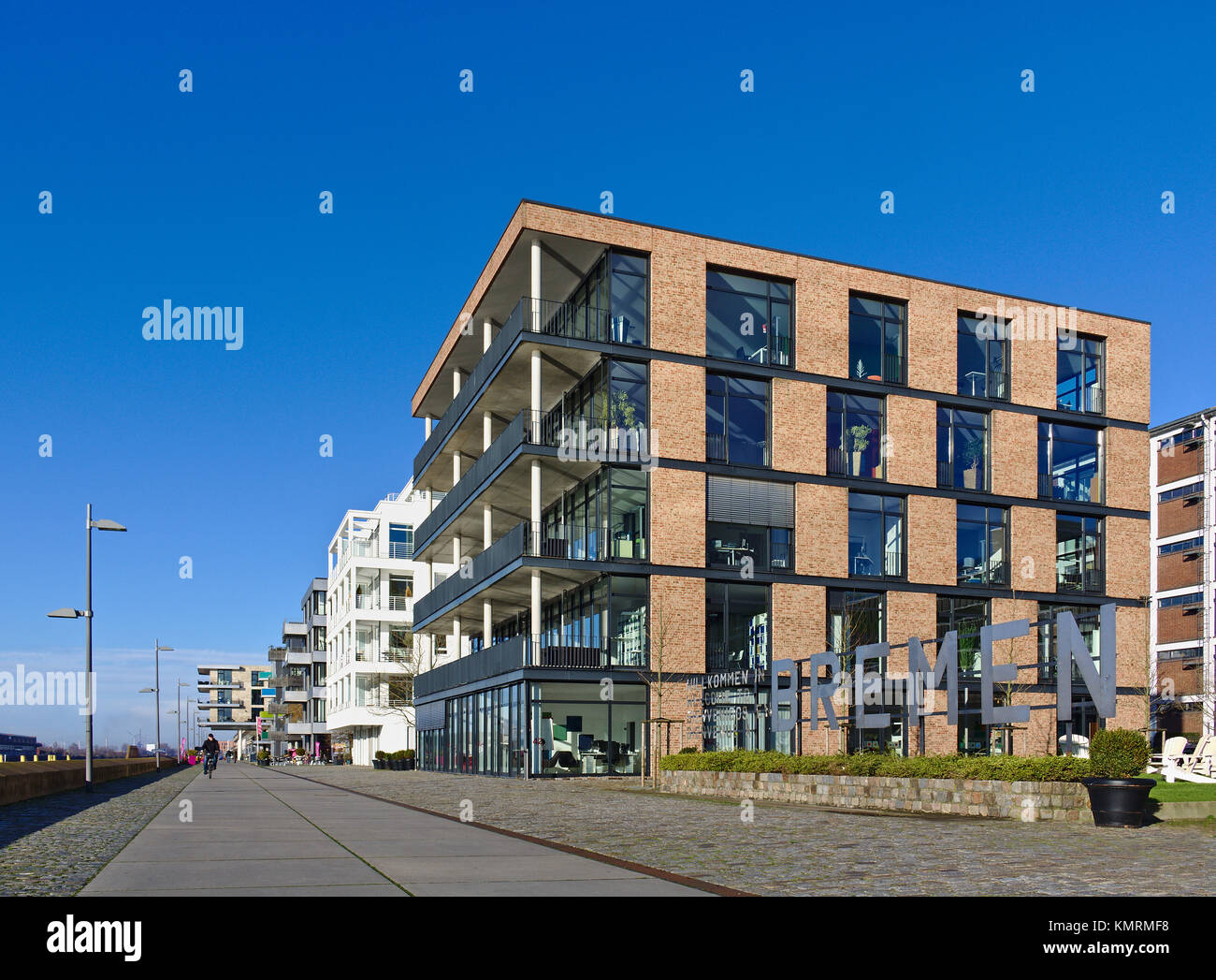 Bremen, Germania - Novembre 25th, 2017 - Spianata nel quartiere Überseestadt con quattro piani ufficio moderno edificio proprio accanto ad un grande cartello in metallo Foto Stock