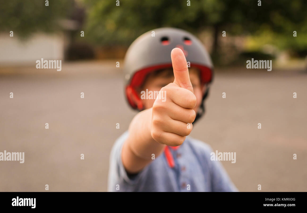 Ragazzo che mostra i pollici in su mentre si indossa il casco Foto Stock