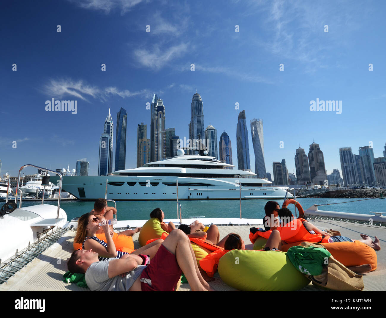 Le persone sulla barca catamarano di Dubai a guardare verso il cielo della città e cielo e raschiatori Foto Stock