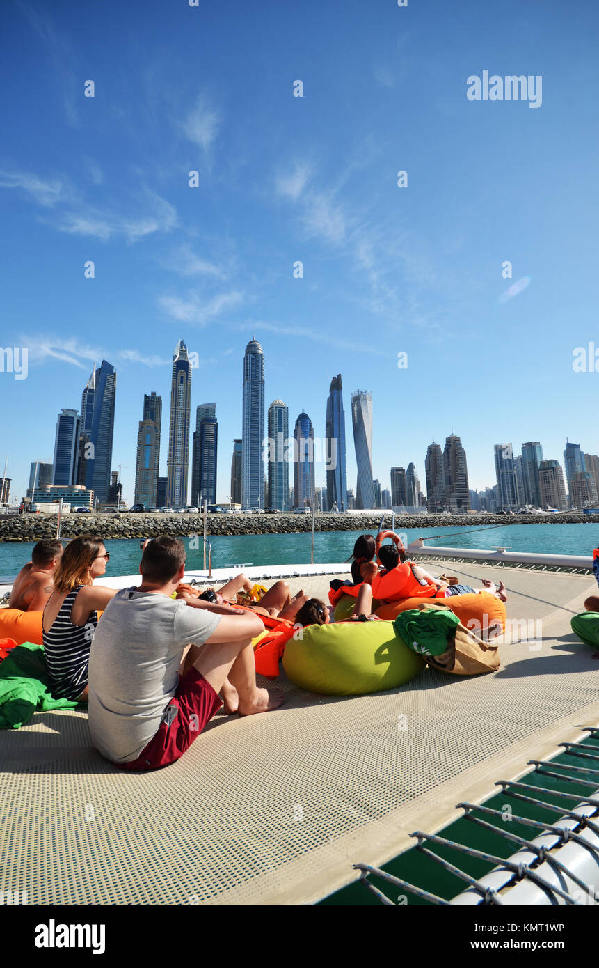 Le persone sulla barca catamarano di Dubai a guardare verso il cielo della città e cielo e raschiatori Foto Stock
