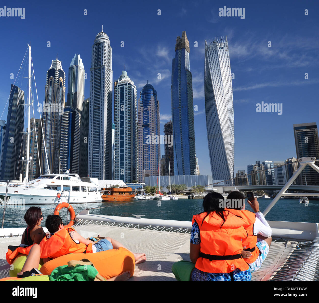 Le persone sulla barca catamarano di Dubai a guardare verso il cielo della città e cielo e raschiatori Foto Stock