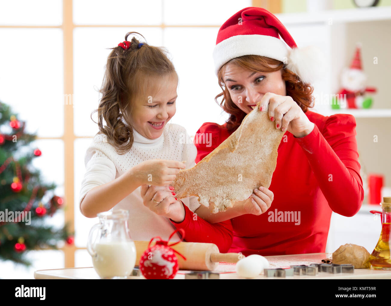 Madre e figlia la cottura biscotti di Natale a decorate albero. Mamma e Bambino cuocere i dolci di Natale. Famiglia con bambini festeggiano il Natale a casa. Foto Stock