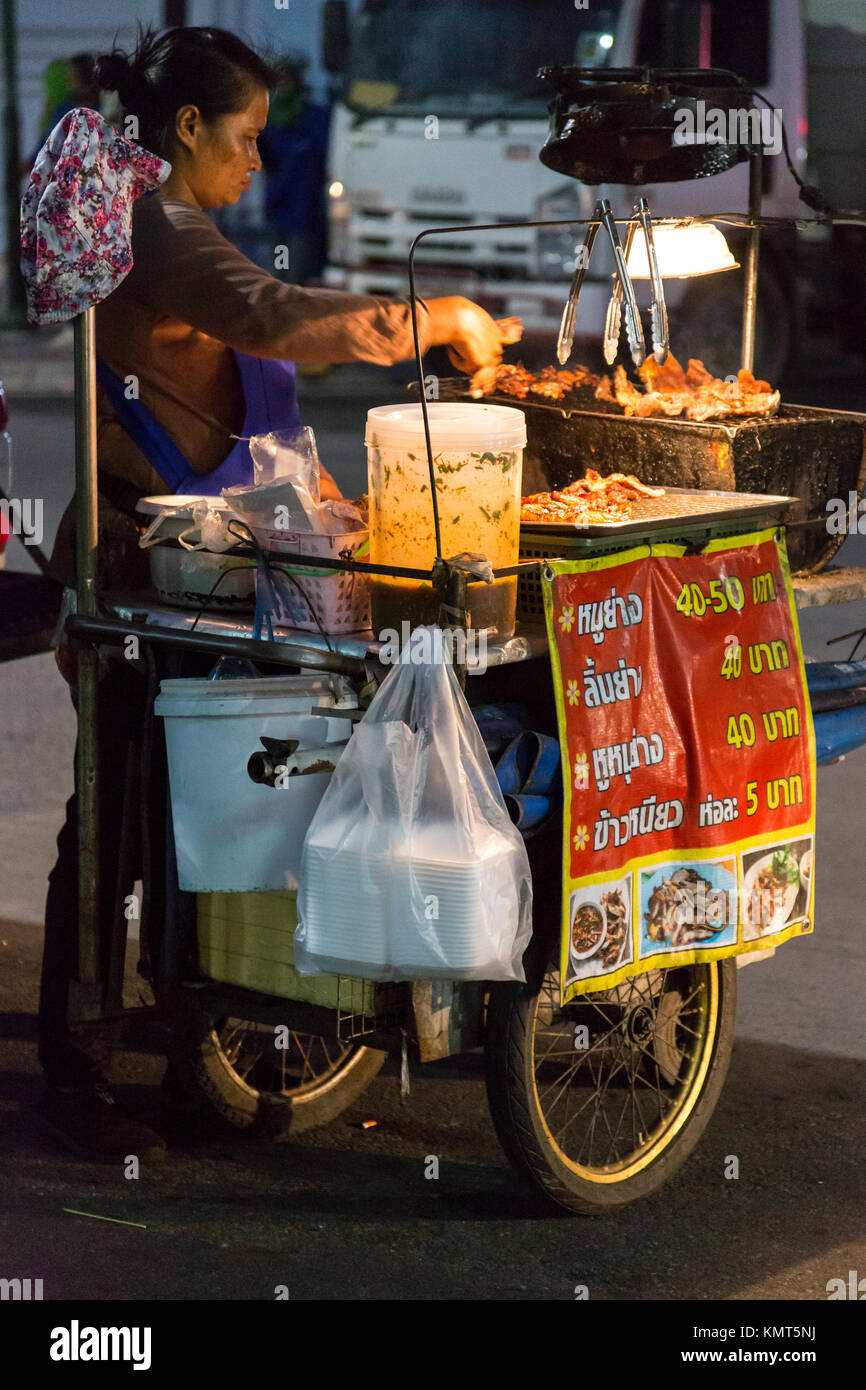 Bangkok, Tailandia. Cucina di strada produttore presso il suo stand durante la notte. Foto Stock