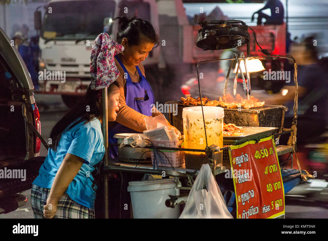 Bangkok, Tailandia. Cucina di strada produttore presso il suo stand durante la notte. Foto Stock