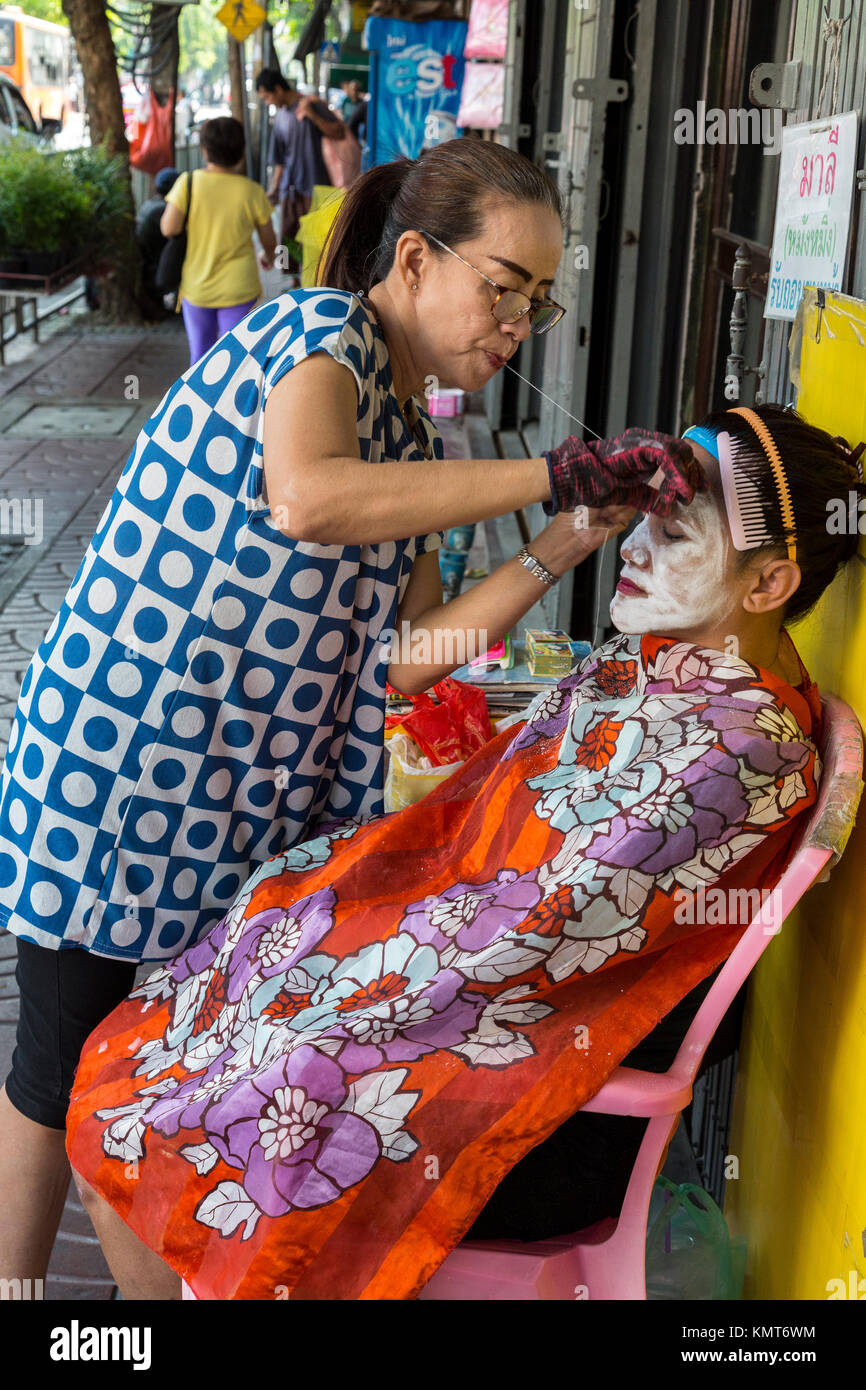 Bangkok, Tailandia. Epilazione del viso da un medico sulla strada a Chinatown. Foto Stock