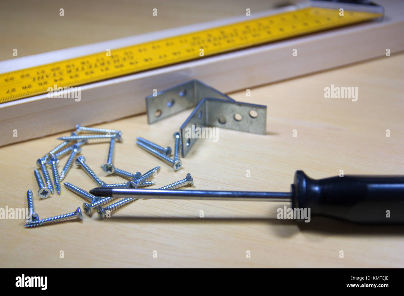 Una chiusura di attrezzi di falegnameria, una regola su una stecca di legno in cui stanno andando a mettere alcune viti. Foto Stock