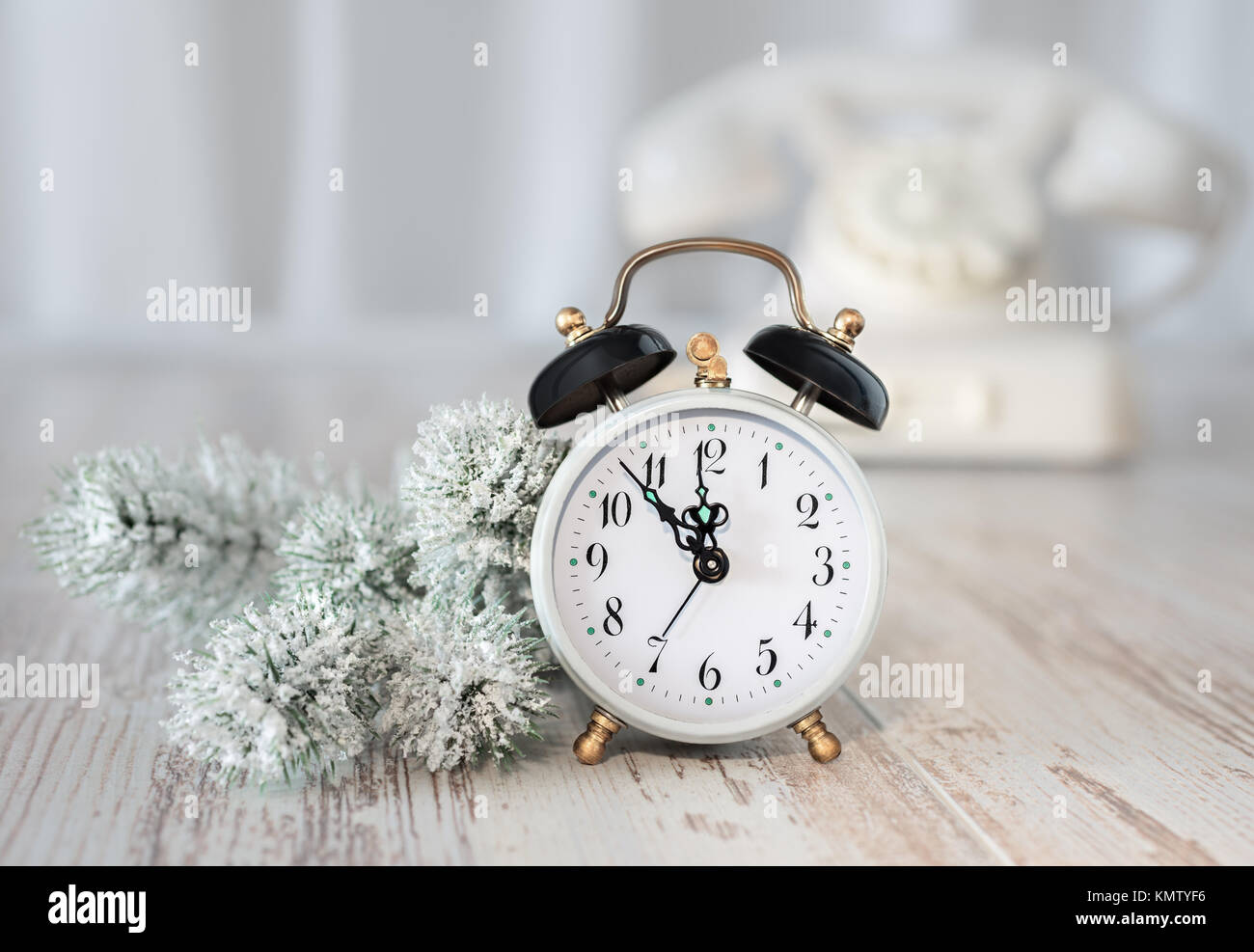 Il vecchio orologio sveglia che mostra cinque a mezzanotte e white wintage telefono. Felice Anno Nuovo! Foto Stock