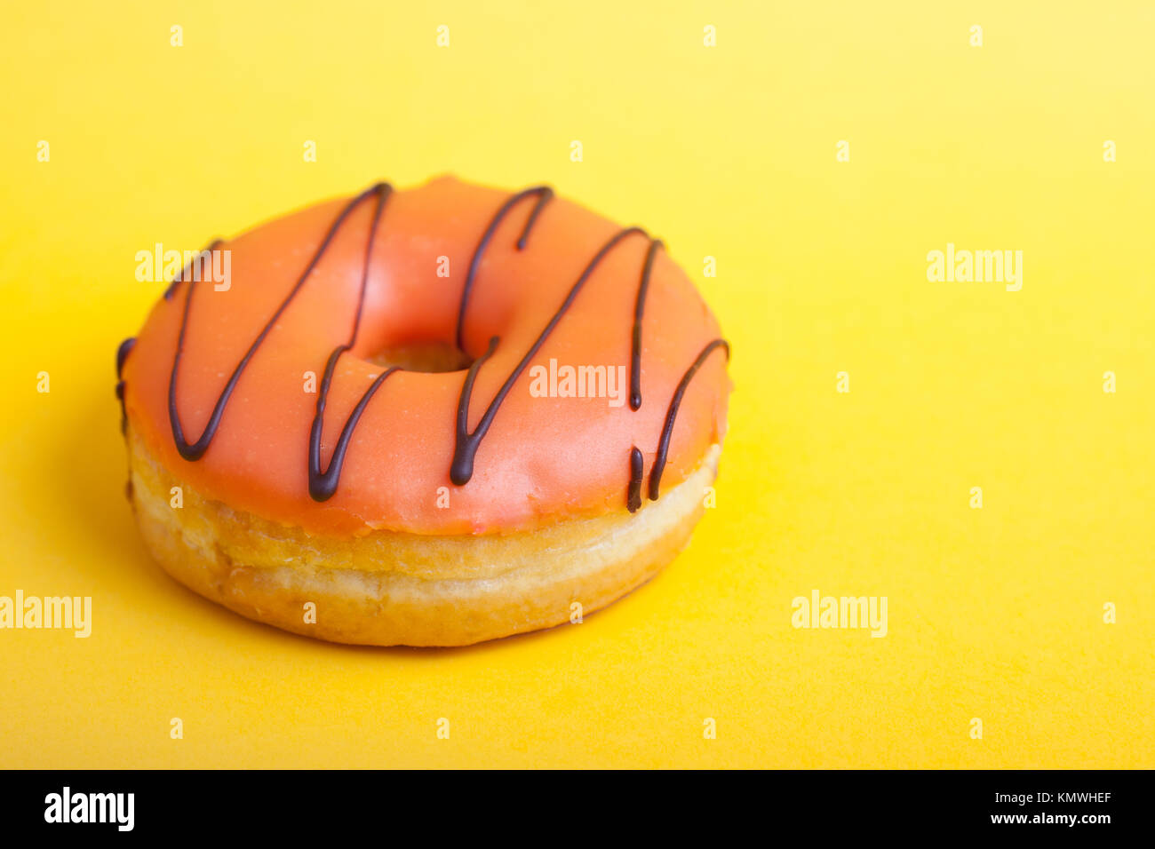 Orange ciambella con glassa su sfondo giallo. Vista dall'alto. La minima nozione. Foto Stock
