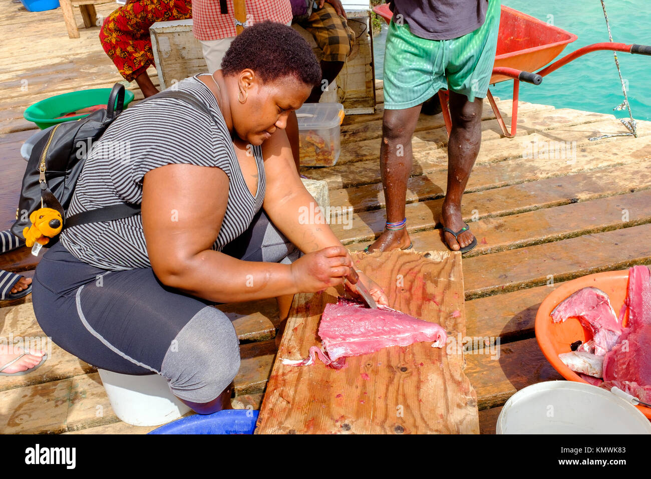 Donna l'eviscerazione e il taglio di un fresco il tonno pescato a Santa Maria pier, Capo Verde, Africa Foto Stock