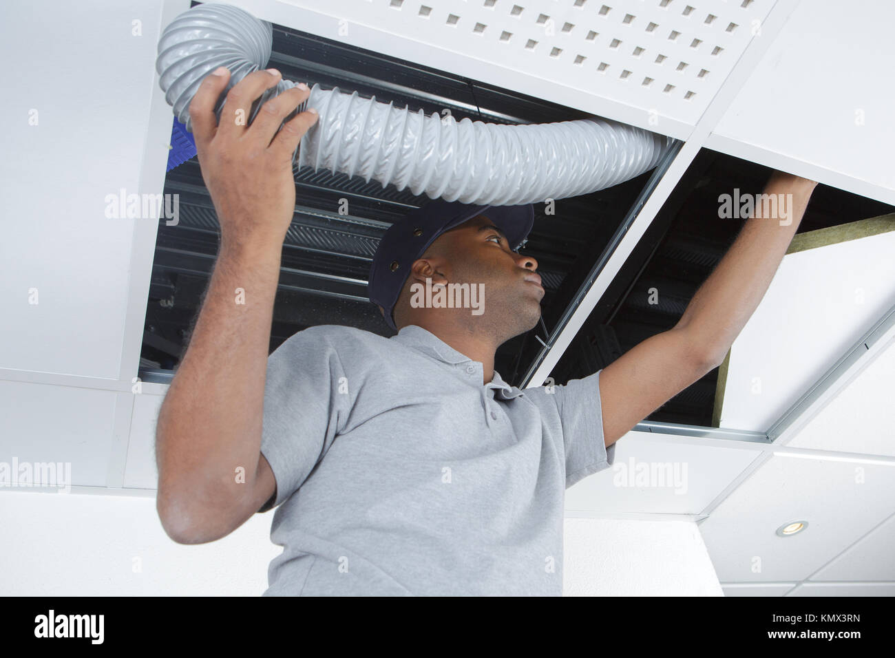 Uomo di raccordo tubo flessibile di ventilazione in roofspace Foto Stock