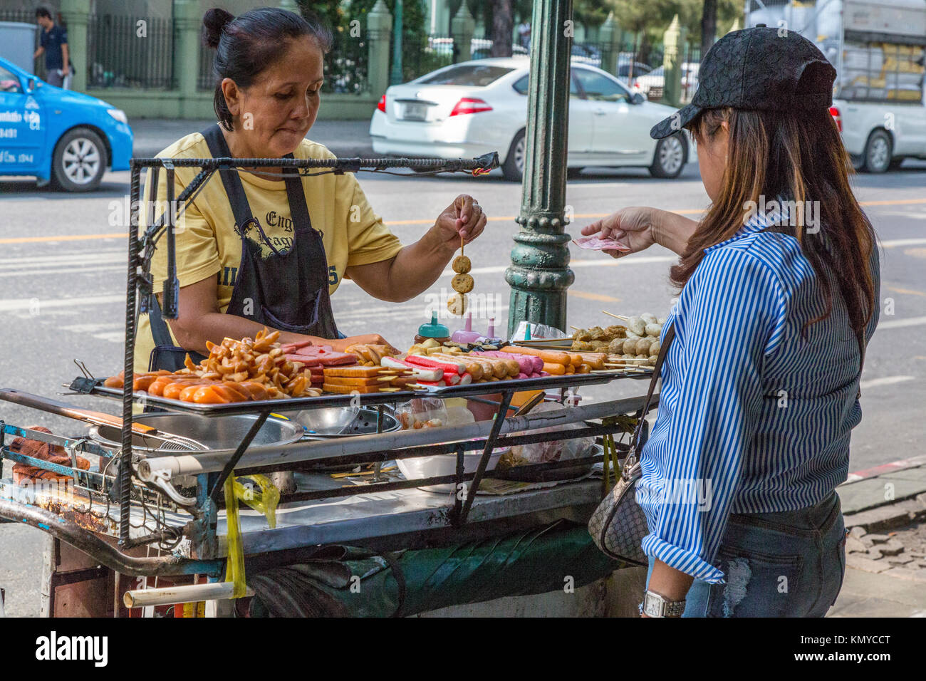 Bangkok, Tailandia. Cucina di strada fornitore che offre spiedini, Hot Dogs, arrosti di carni rosse. Foto Stock