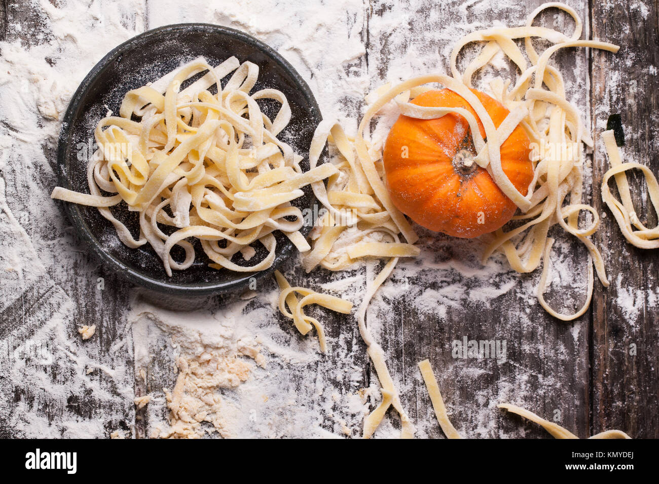 Vista dall'alto su materie pasta fatta in casa con la zucca e farina su un vecchio tavolo di legno. Vedere serie Foto Stock