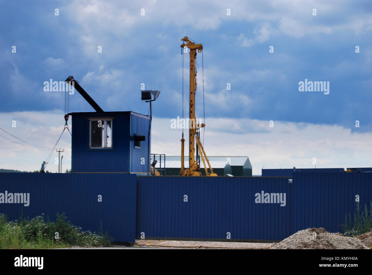 Yellow Crane dietro il recinto di blu. Costruzione di attrezzature industriali. Foto Stock
