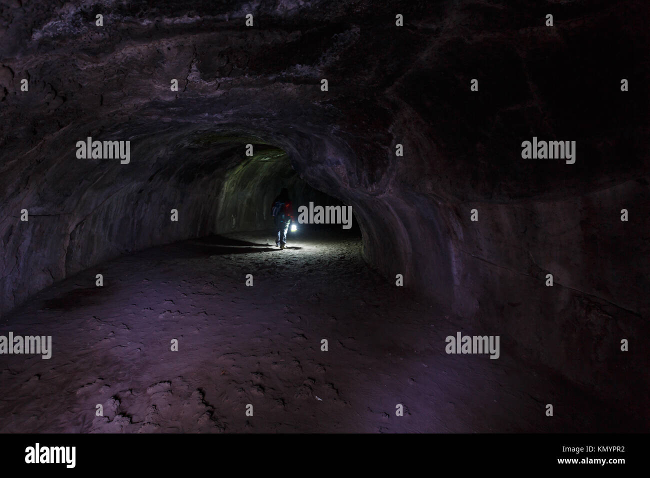 Escursionista con la lanterna passeggiate attraverso vulcanico di Lassen Parchi Nazionali tubo di lava di una grotta fatta durante il fuso del flusso di lava Foto Stock