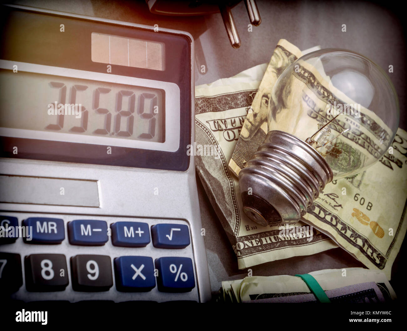 Calcolatrice e denaro accanto a una lampadina, il concetto di risparmio energetico Foto Stock