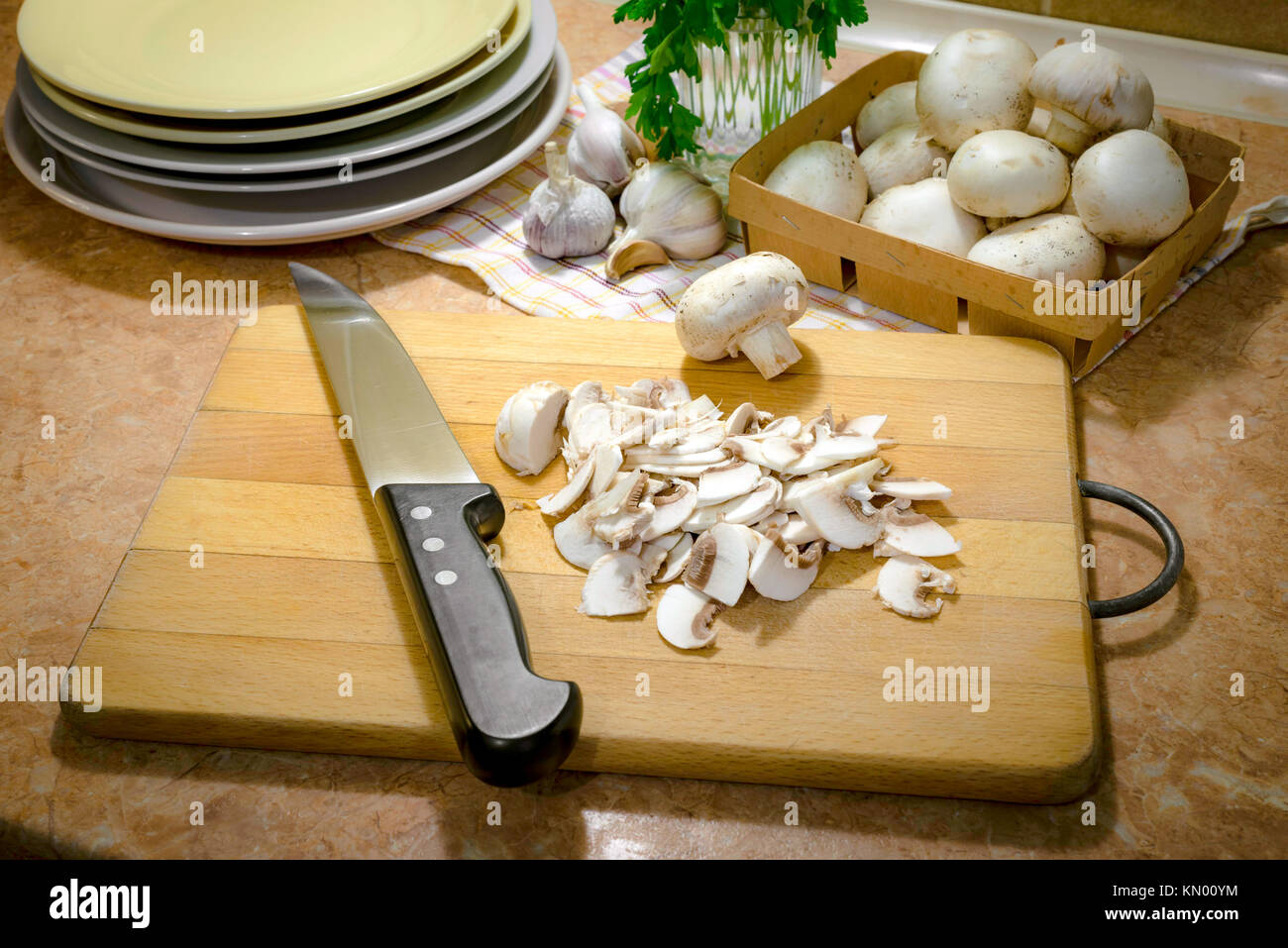 Preparazione di 'funghi trifolati' (a fette sottili gli champignon cotti con olio, aglio e prezzemolo) Foto Stock