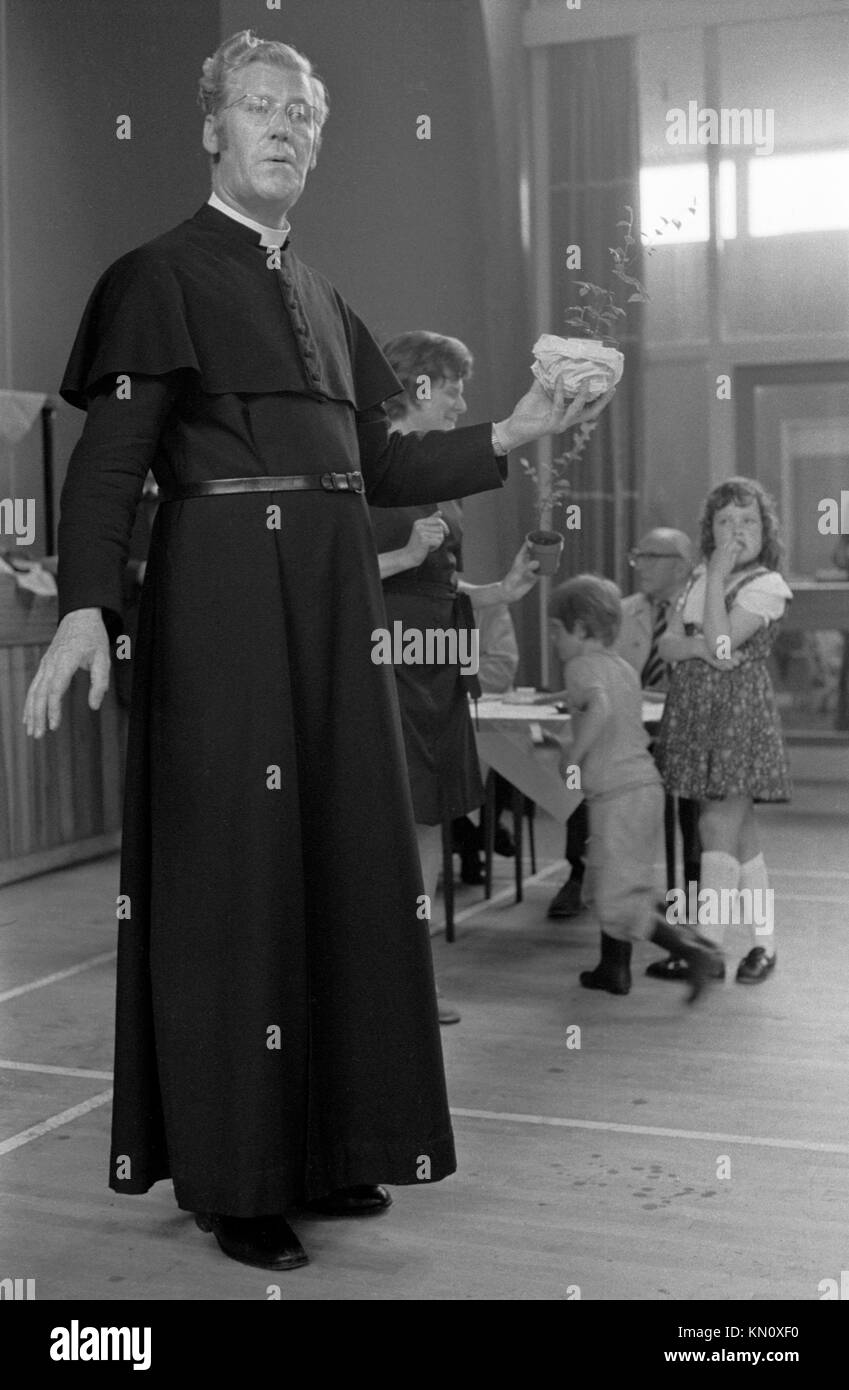 Village Fete 1970s England, all'interno della palestra della scuola locale, con il maltempo e le sue piogge. Il vicario che distribuisce i premi. 1972 Solihull Warwickshire UK HOMER SYKES Foto Stock