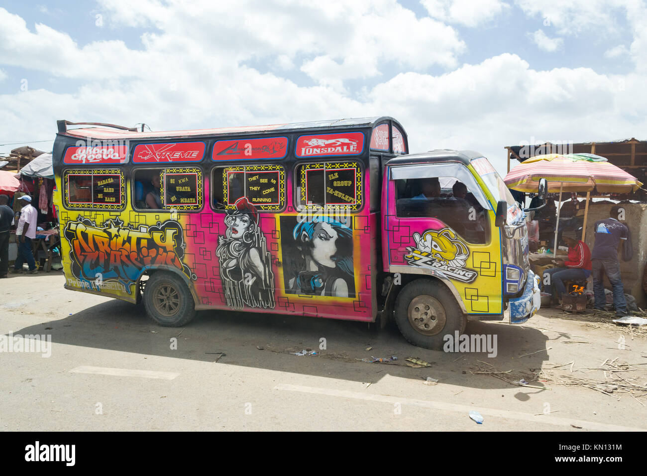 Un bus luminosamente decorate con arte arrestata dal lato della strada accanto ad una piccola platea, Nairobi, Kenya, Africa orientale Foto Stock