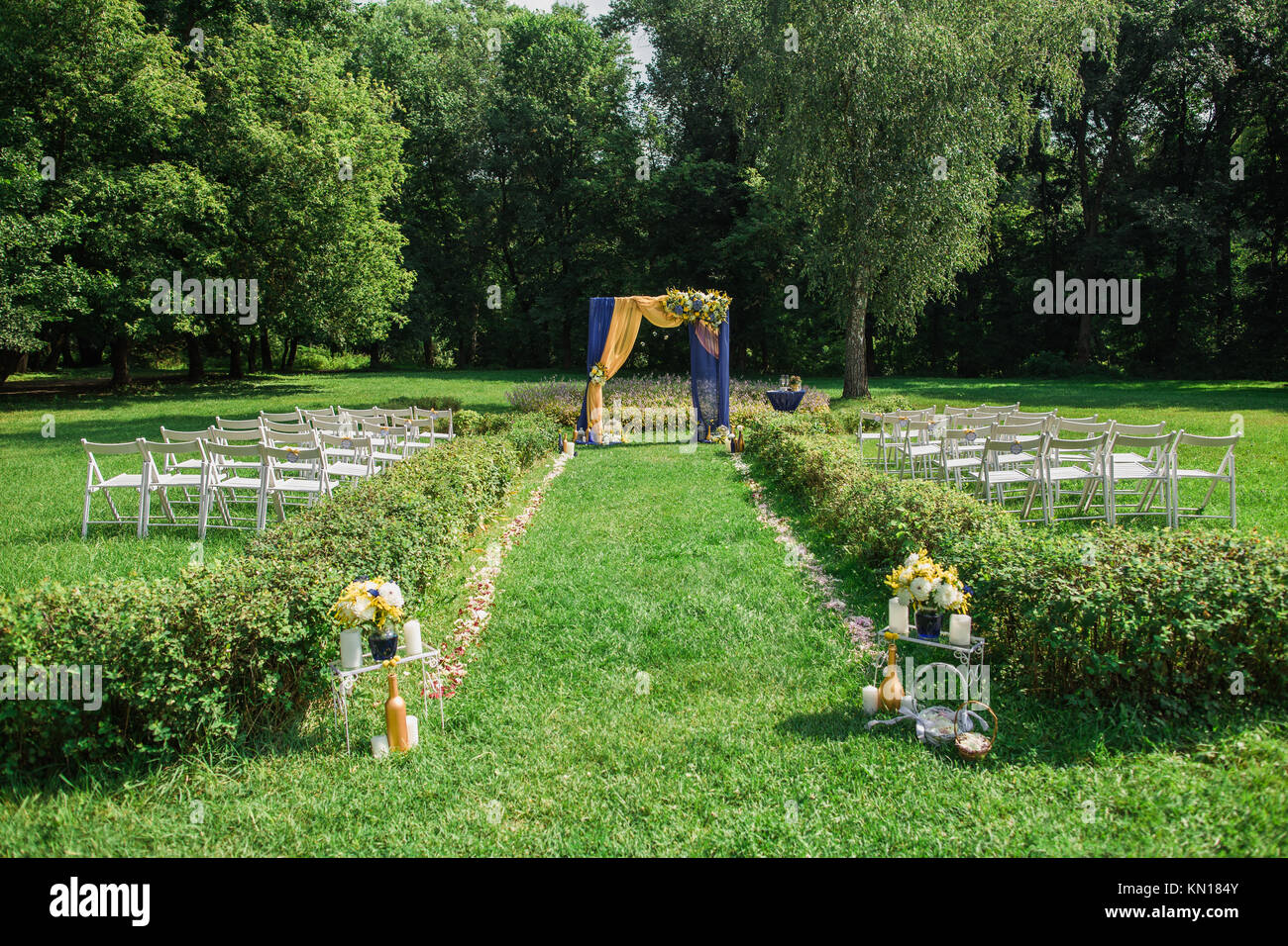 Le impostazioni di bella all'aperto per la cerimonia nuziale e la celebrazione. Splendidamente decorate arco con fiori e tante vuote con sedie in legno in luogo scenico Foto Stock