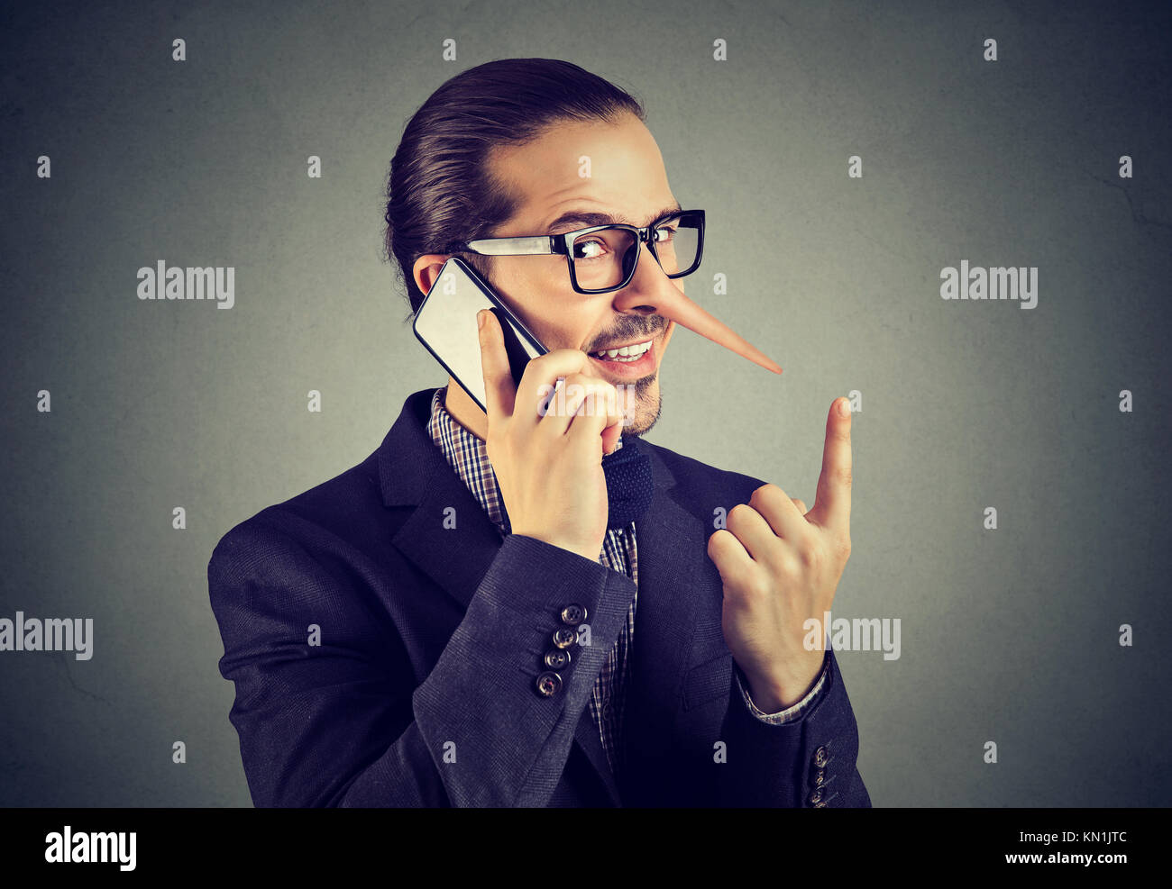Sly bugiardo business man con il naso lungo parlando al telefono cellulare isolata sul muro grigio Sfondo. Foto Stock