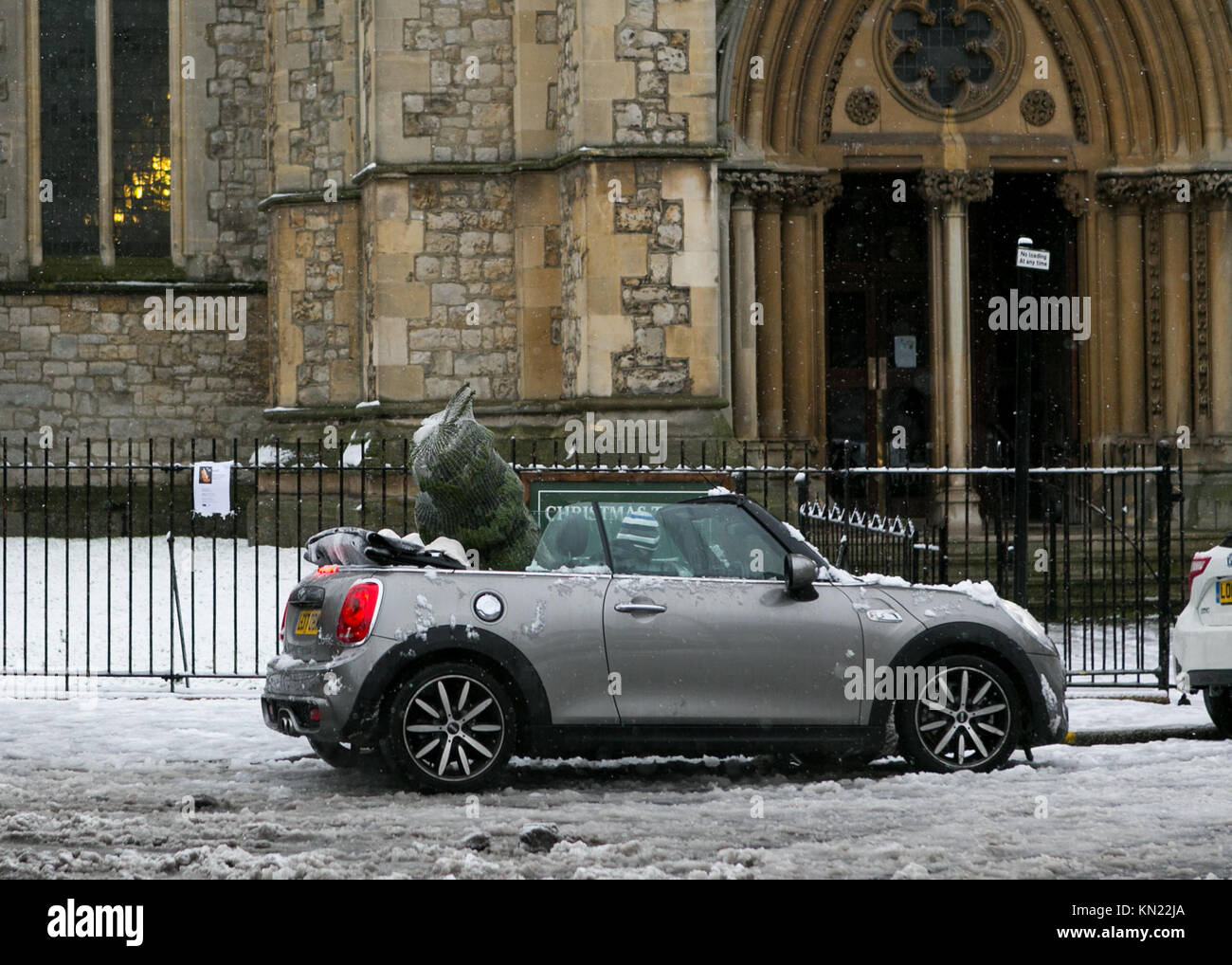 Stoke Newington, Hackney, Londra, Regno Unito. 10 dicembre, 2017. La neve cade a Stoke Newington, Londra. Uomo in Mini con softop verso il basso e verso l'albero di Natale in auto su Stoke Newington Church Street. Credito: Carol moiré/Alamy Live News. Foto Stock