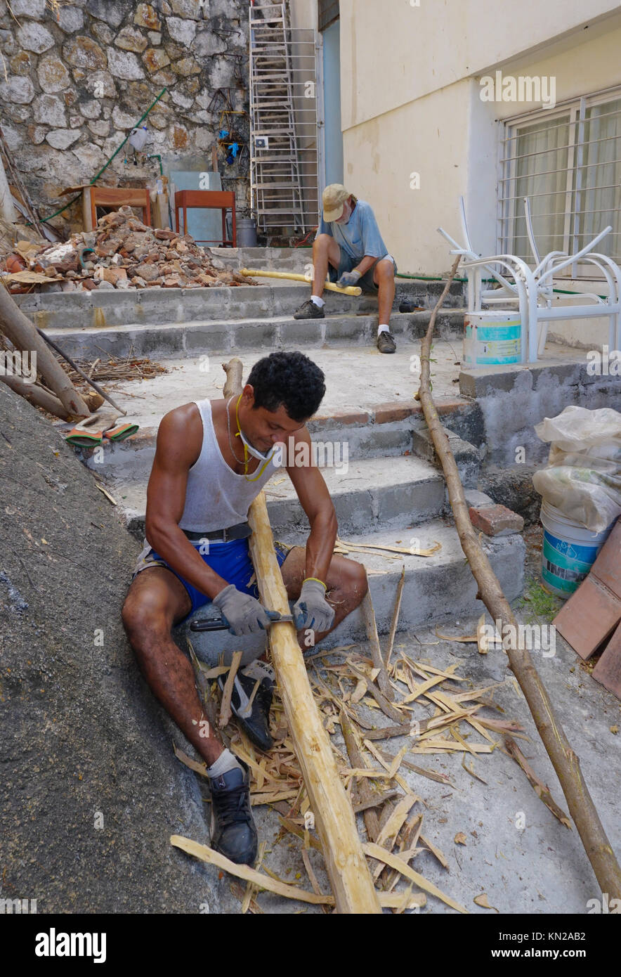 Uomo messicano di corteccia di raschiatura fron rami di alberi per rendere ringhiere per scale. Acapulco, Messico Foto Stock