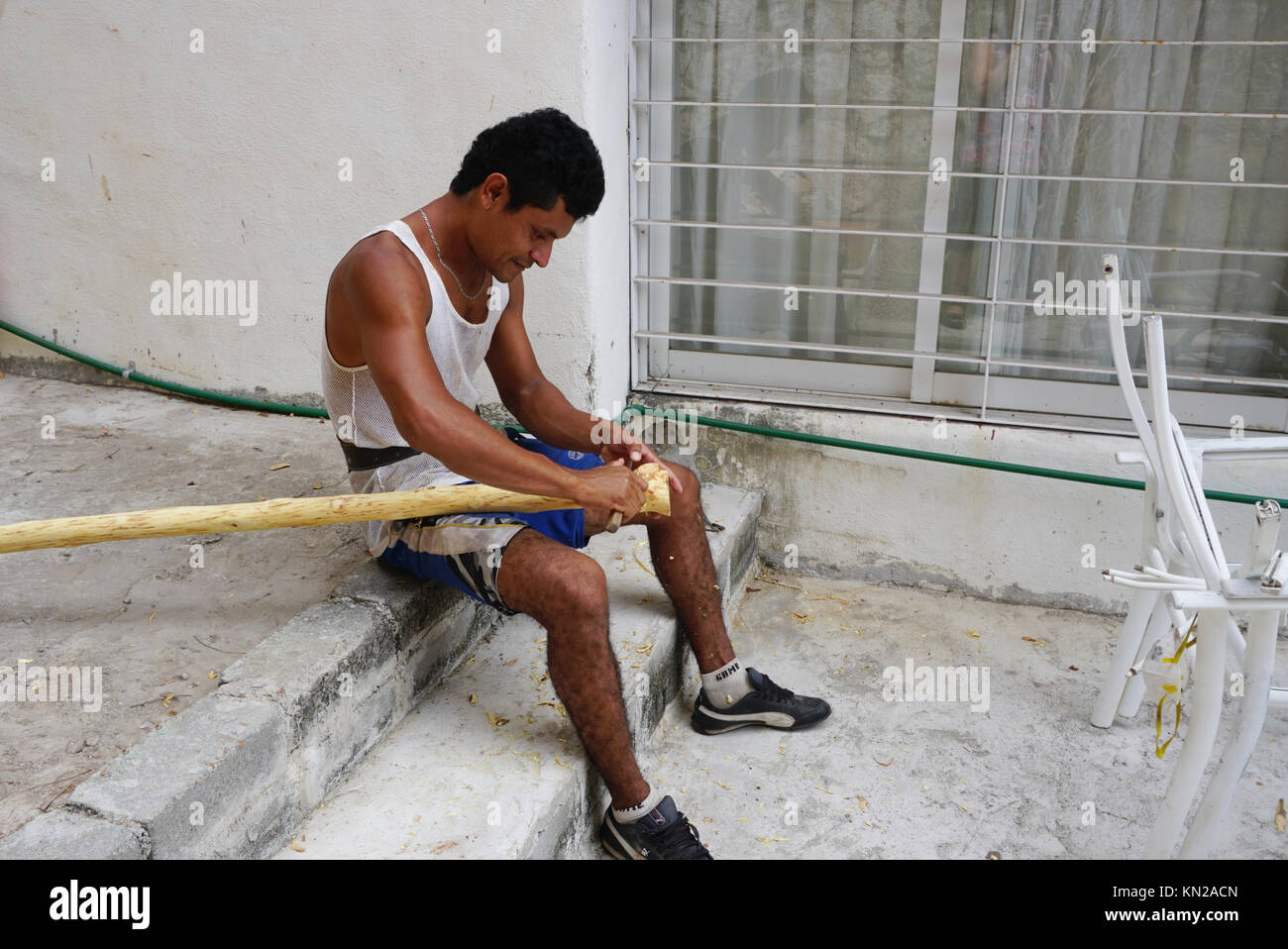 Uomo messicano di corteccia di raschiatura fron rami di alberi per rendere ringhiere per scale. Acapulco, Messico Foto Stock