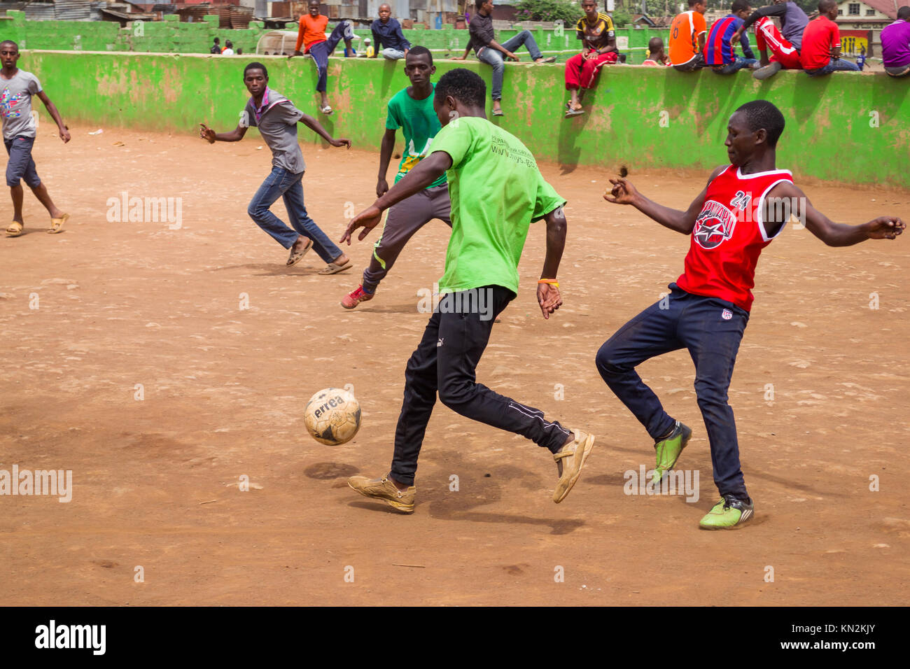 Giovani uomini africani giocando una partita di calcetto su un all'aperto passo polverosi, Huruma, Nairobi, Kenya, Africa orientale Foto Stock