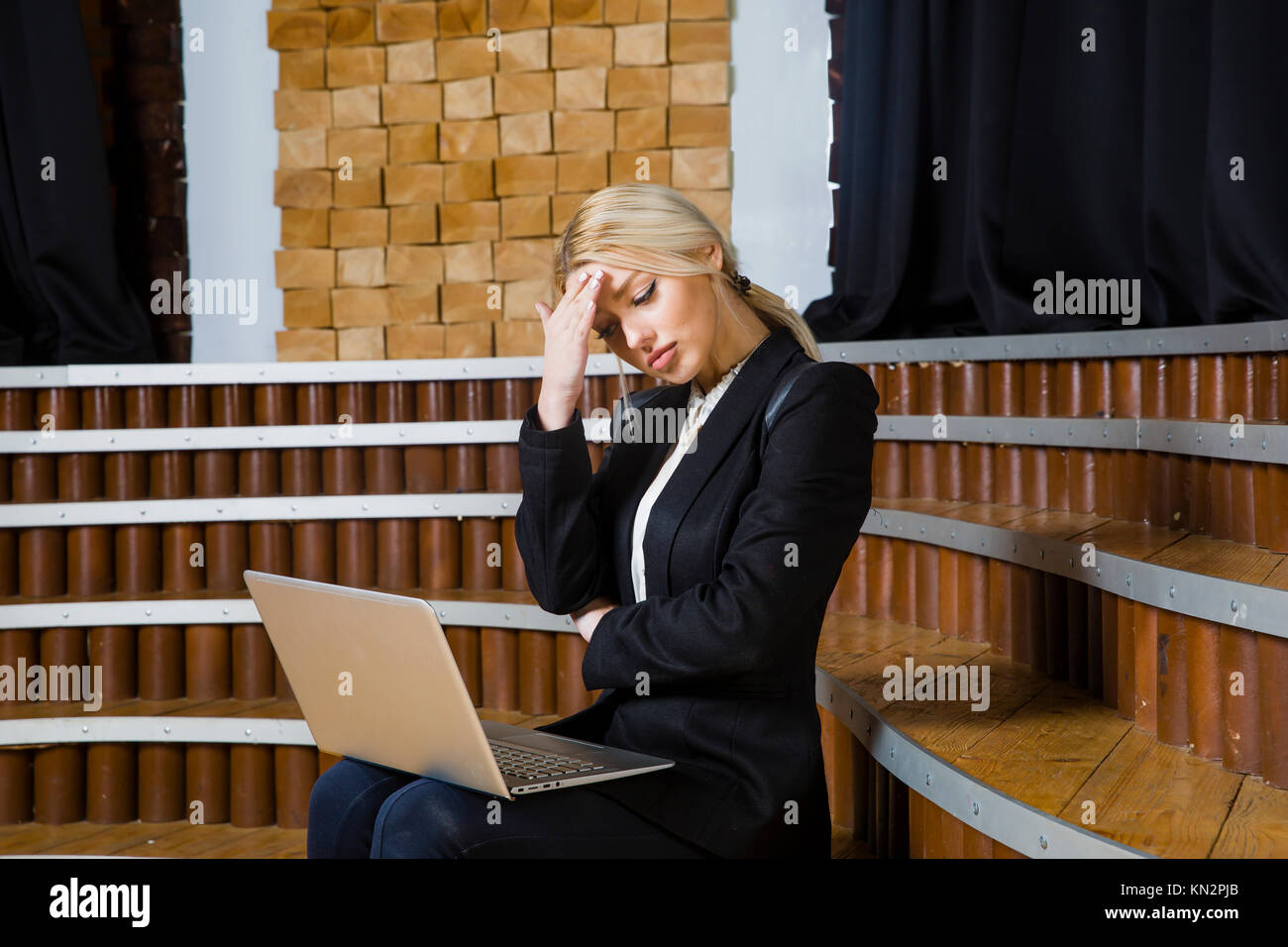 Bella bionda imprenditrice con notebook e laptop in ufficio loft in tuta e. Foto Stock