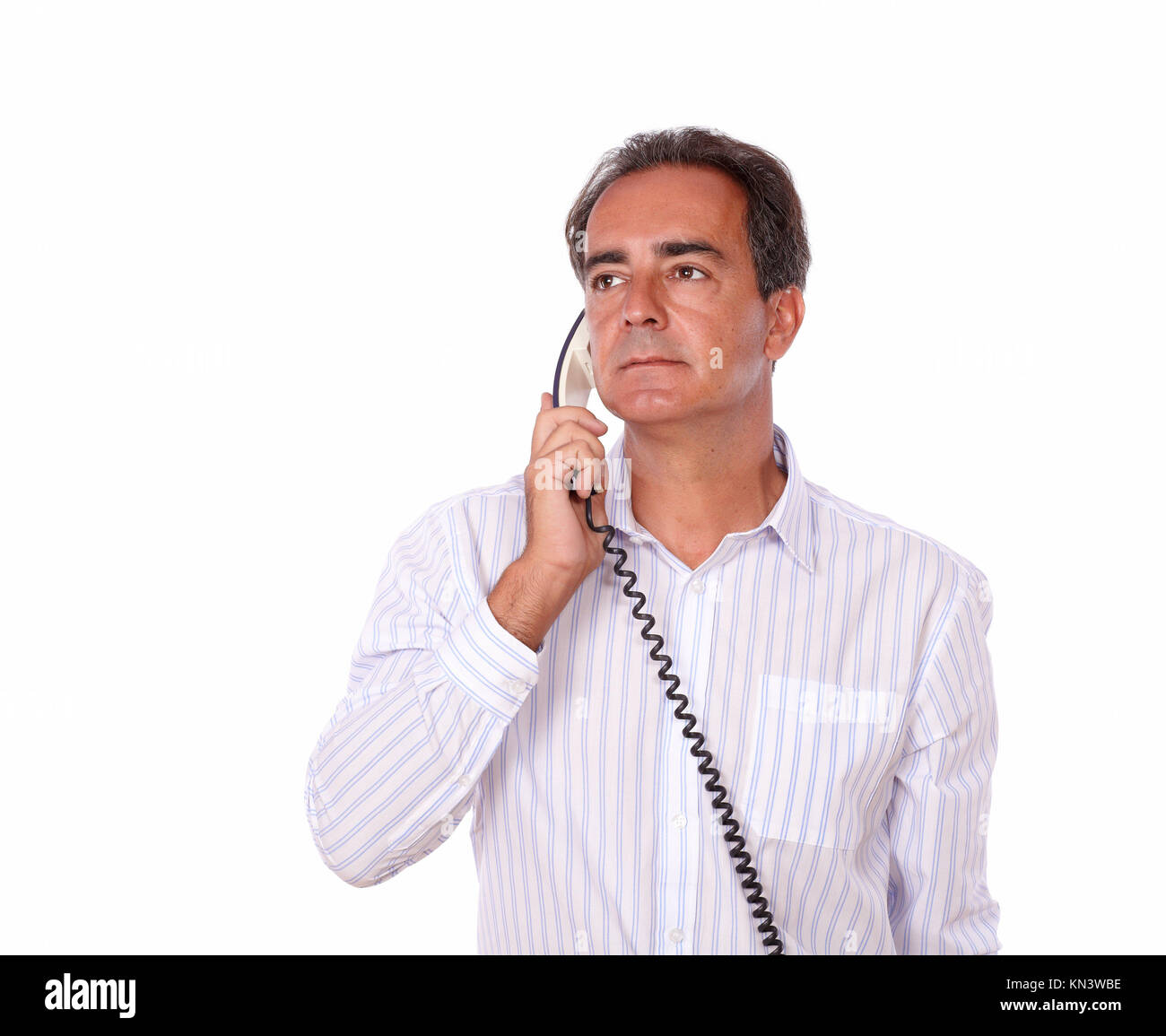 Ritratto di un sofisticato maschio su una camicia bianca parlando al telefono mentre guardando la gente su sfondo isolato - copyspace. Foto Stock