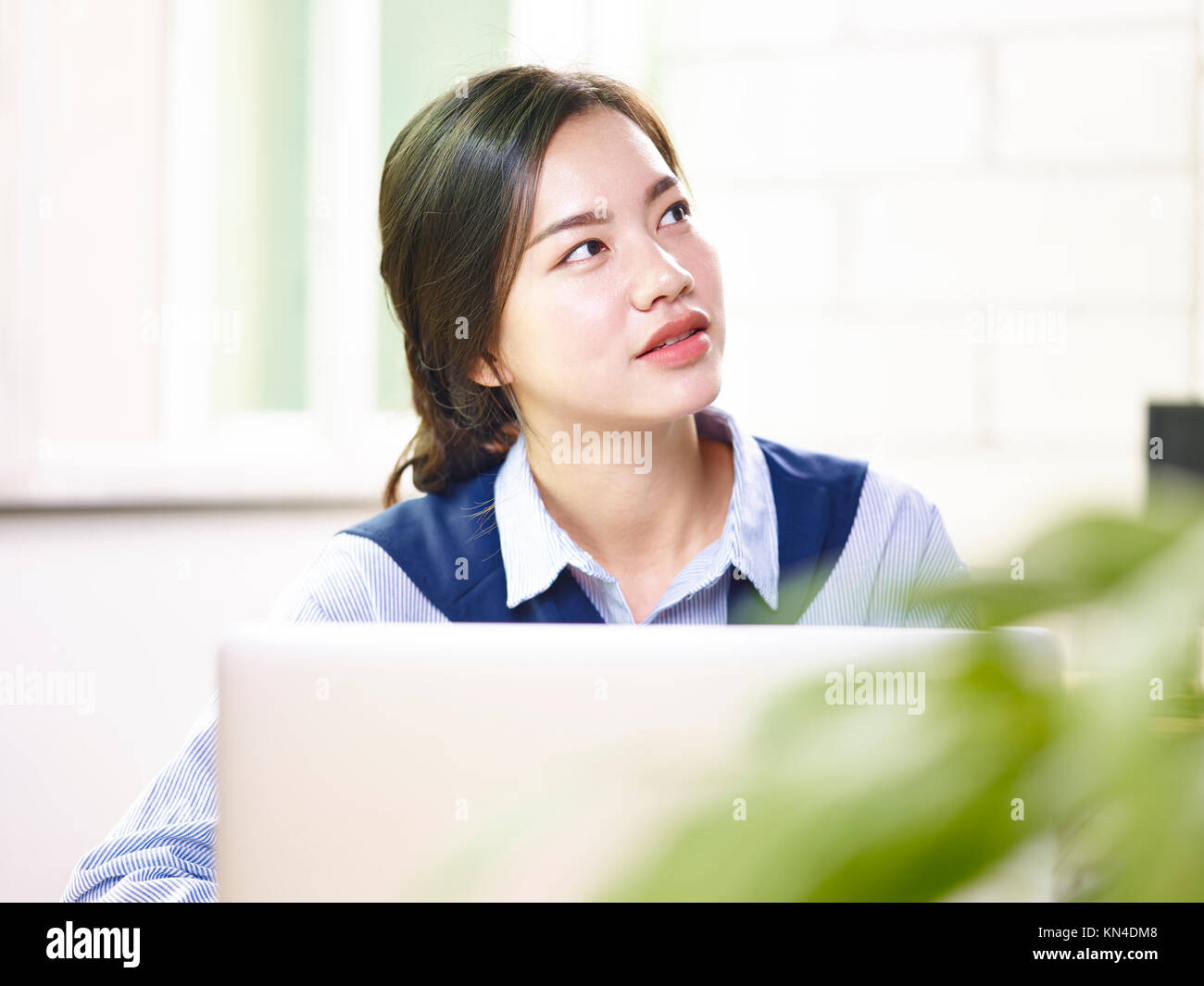 Giovani asiatici imprenditrice cercando mentre si lavora in ufficio utilizzando il computer portatile. Foto Stock