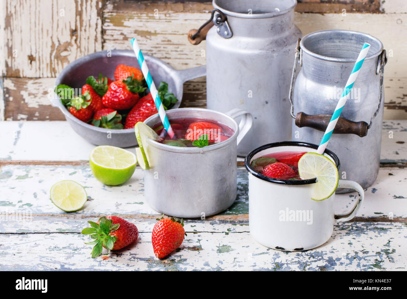 Vintage tazze in metallo con retro cocktail di tubi e acqua-lattine di fragole fatta in casa la limonata, servita con fragole fresche, menta e calce su vecchie wh Foto Stock