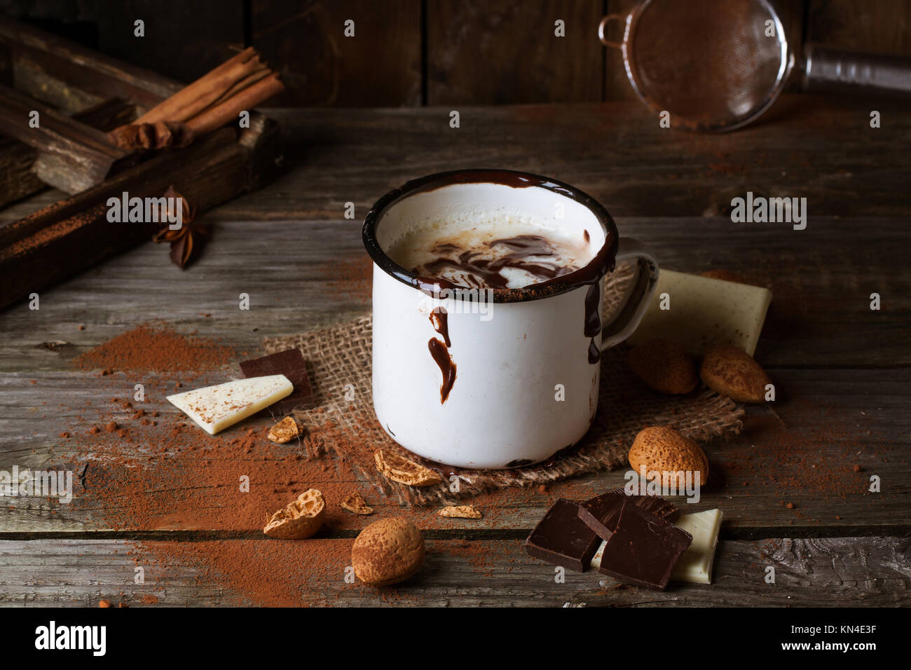 Vintage mug con cioccolata calda servita con pezzetti di bianco e il cioccolato fondente e mandorle sul vecchio tavolo in legno Foto Stock