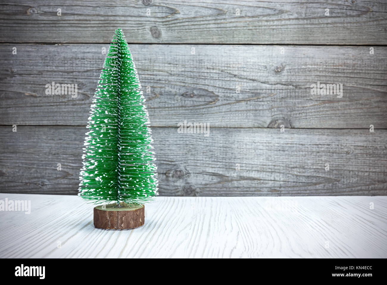 Piccolo albero di Natale artificiale in legno bianco contro rustico schede grigio Foto Stock