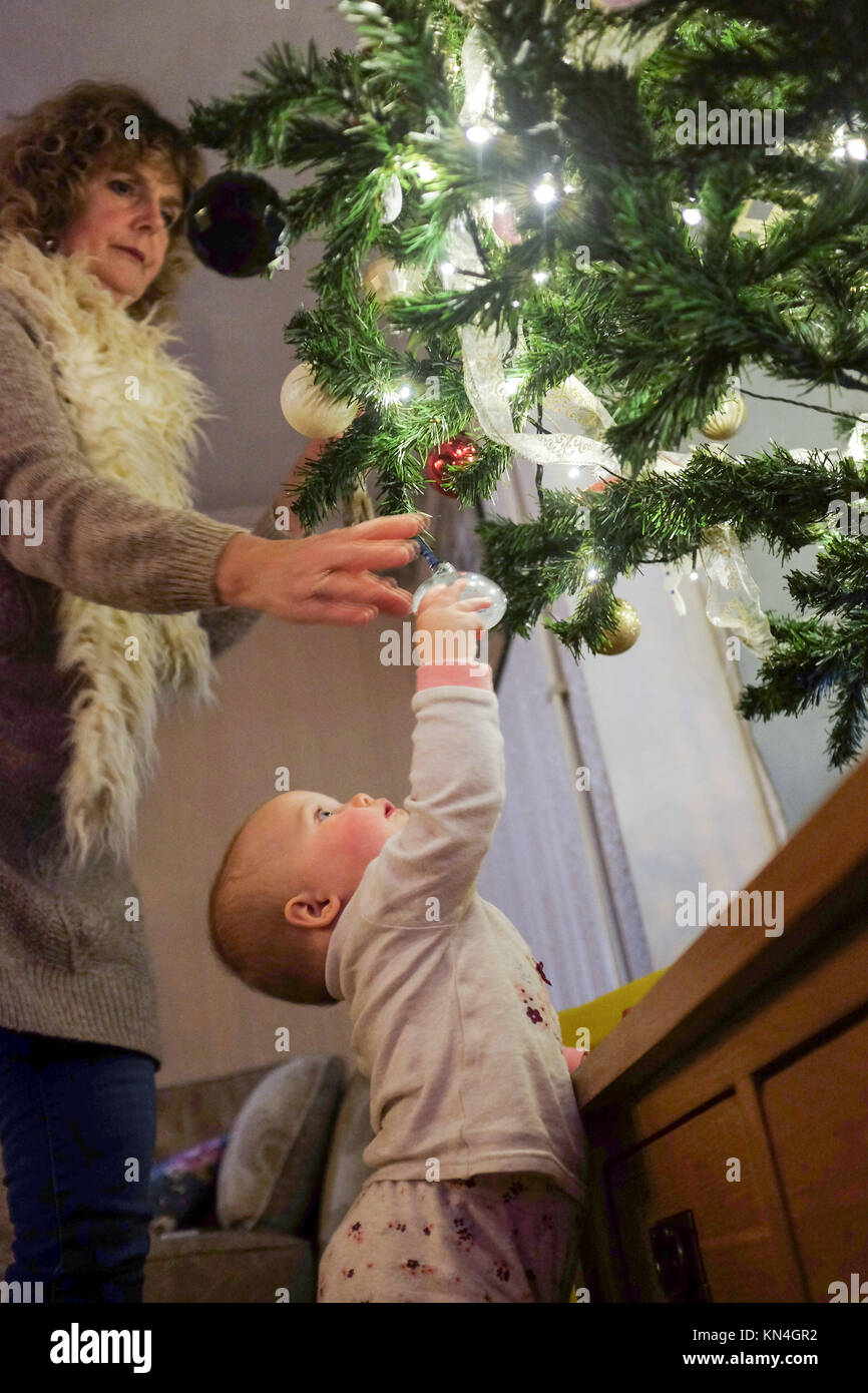 Natale 2017 - molto carino di un anno di età Baby girl toddler affascinato da albero di Natale luci Foto Stock