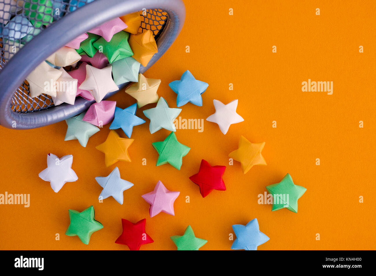 Origami colorati lucky stelle fuoriuscita di un bin. Sfondo giallo. Foto Stock