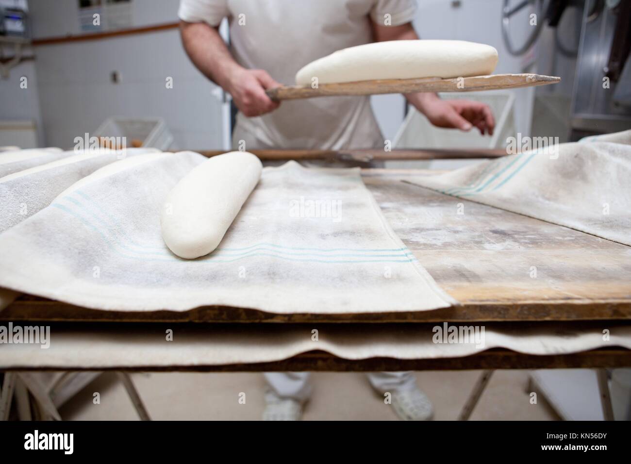 Baker tenendo il forno con la fetta di pane crudo. Processo di fabbricazione del pane spagnolo. Foto Stock