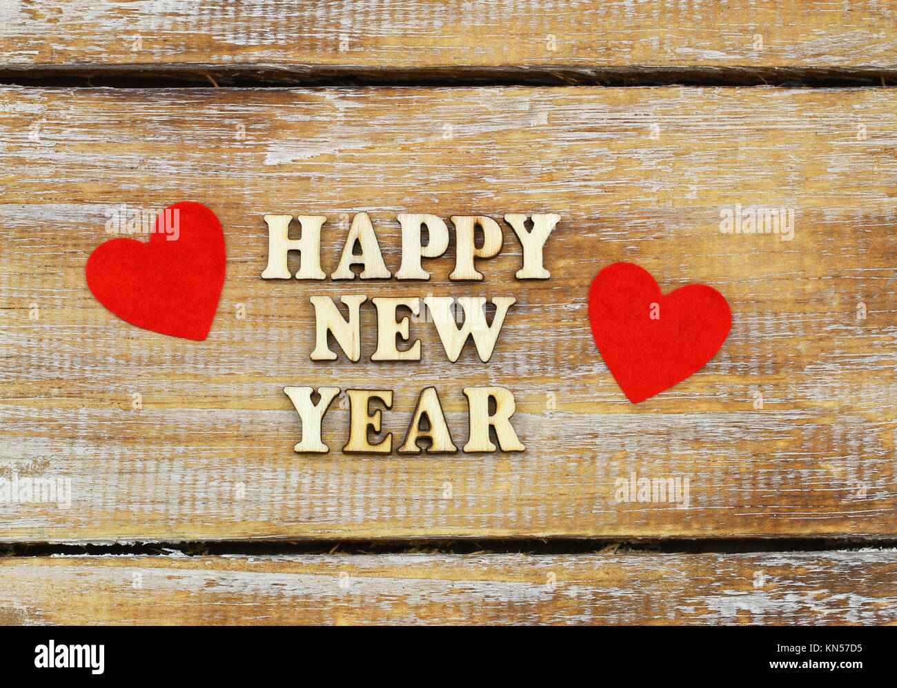 Felice Anno Nuovo scritto con lettere di legno sulla superficie di rustico e due cuori rossi Foto Stock