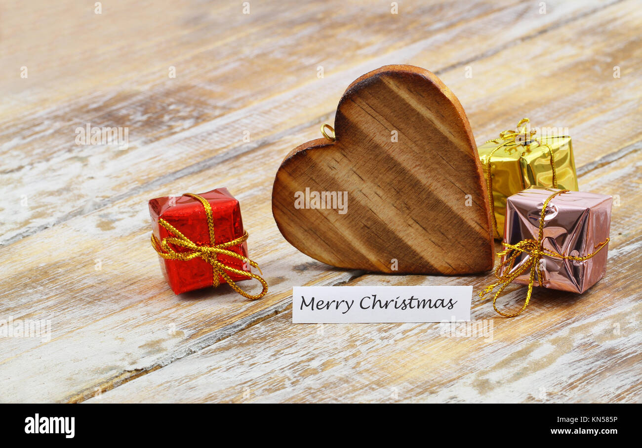 Merry Christmas card con cuore in legno lucido e i regali di Natale Foto Stock