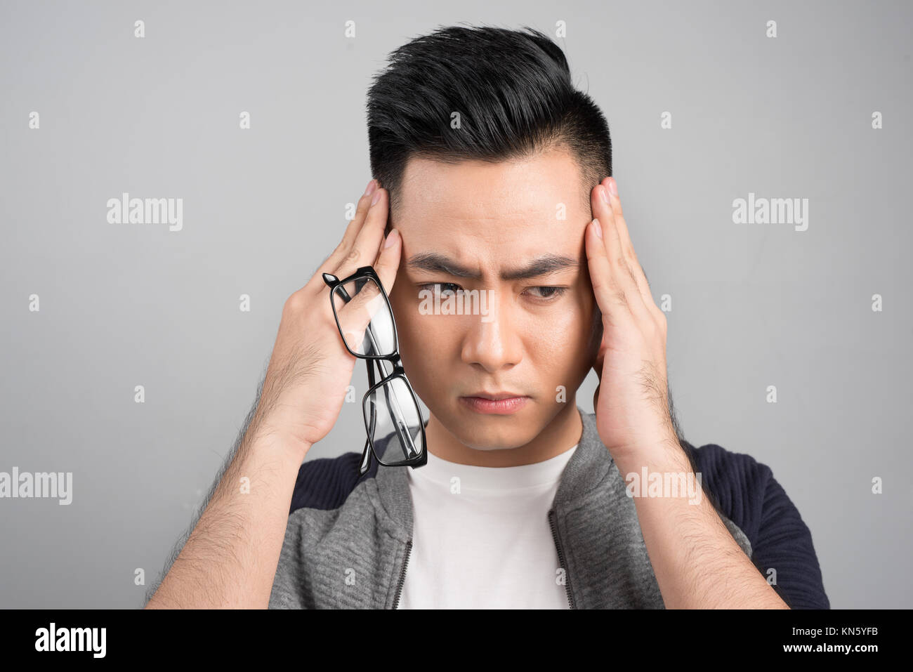 Terribile mal di testa. Frustrati giovane uomo di toccare la sua testa con le mani Foto Stock