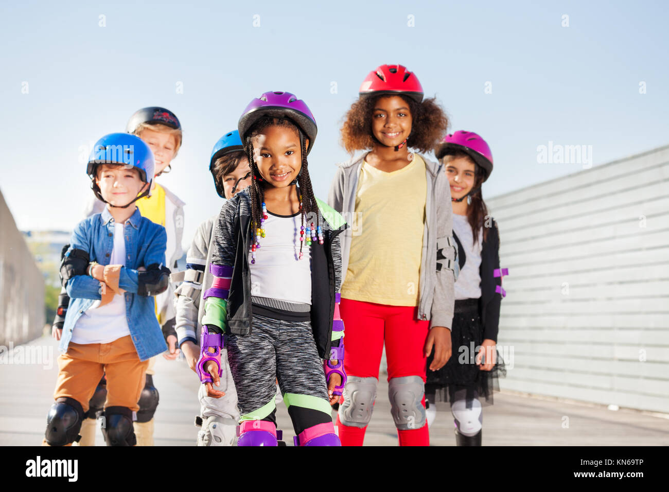 Gruppo di felice ragazzi sportivo, preteen ragazzi e ragazze in sicurezza con i rollerblade ingranaggio esterno Foto Stock