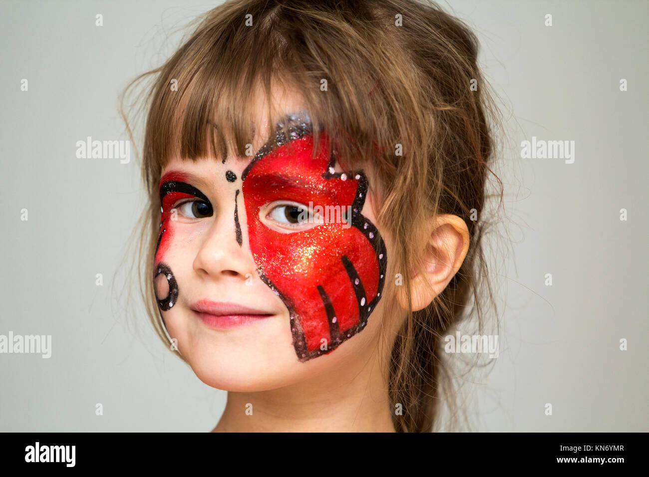 Ritratto di graziosa bambina con farfalla dipinto sul suo viso Foto Stock