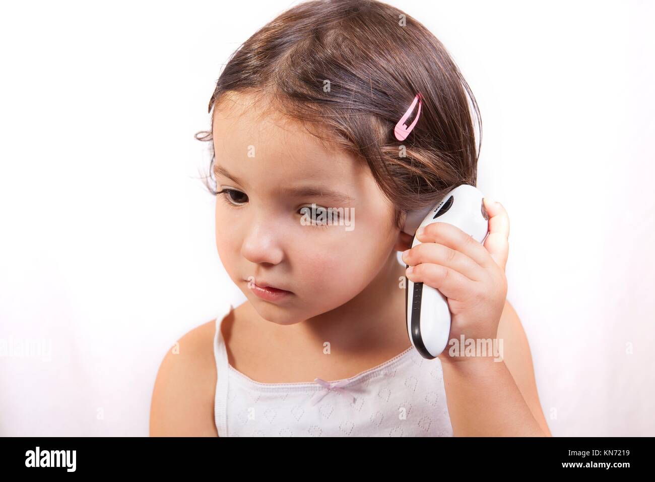 Bambina con orecchio parlando termometro elettronico prendendo se stessa la temperatura. Isolato su sfondo bianco. Foto Stock