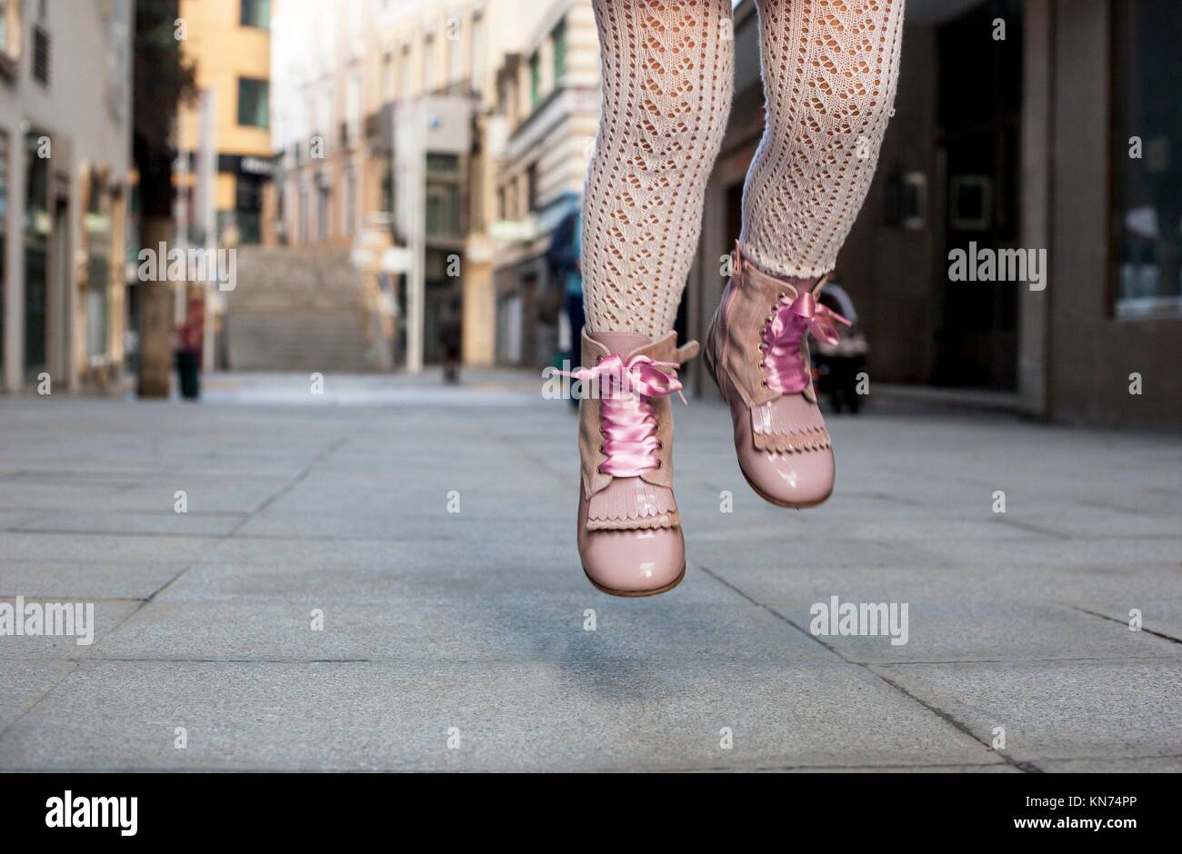Felice bambina di tre anni con salto in raso rosa stivali in pizzo sulla città. Close up. Foto Stock