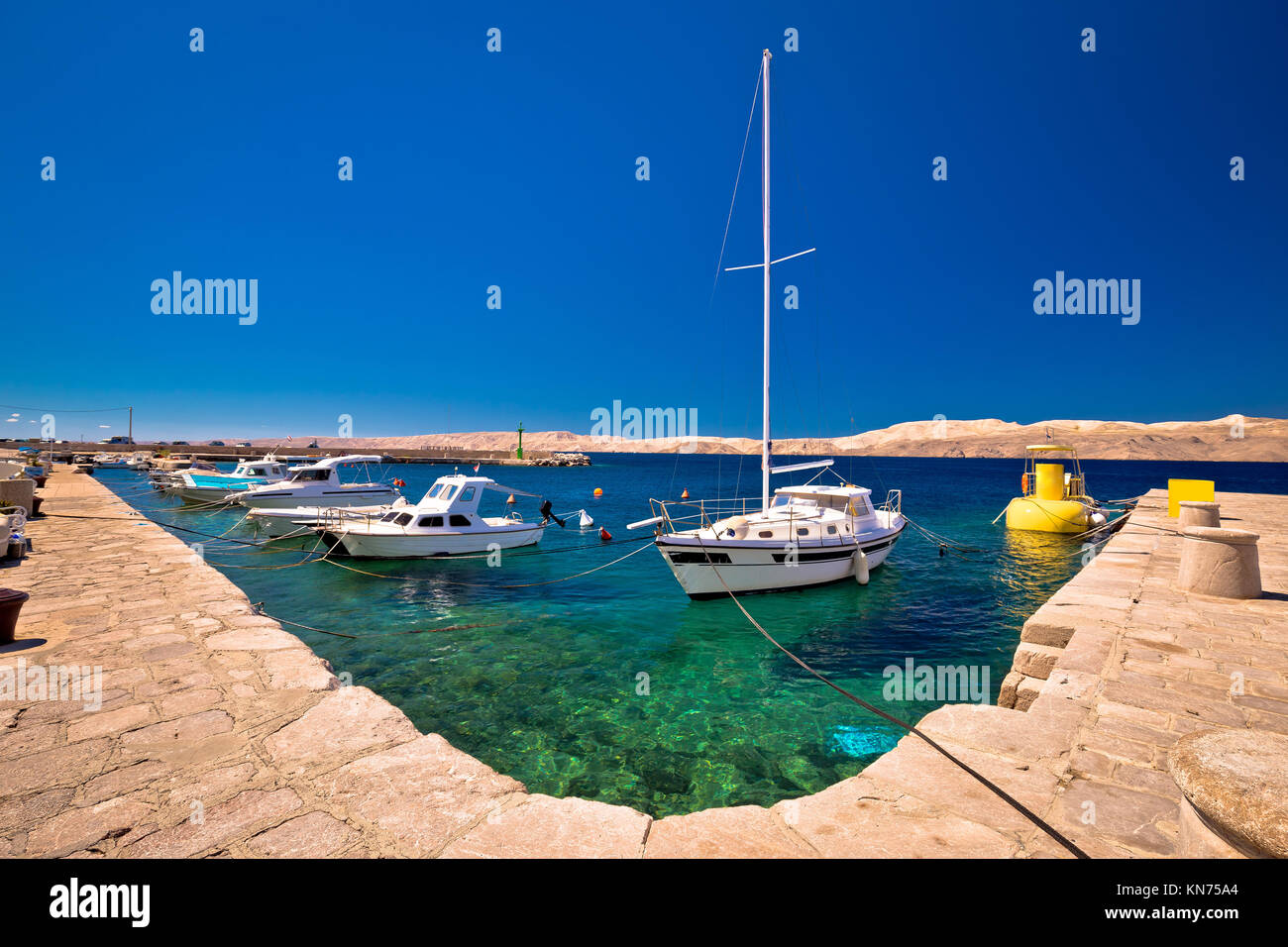 Barca galleggiante sul mare turchese nel canale di Velebit, con isola deserta di Pag sfondo, Karlobag, Croazia Foto Stock